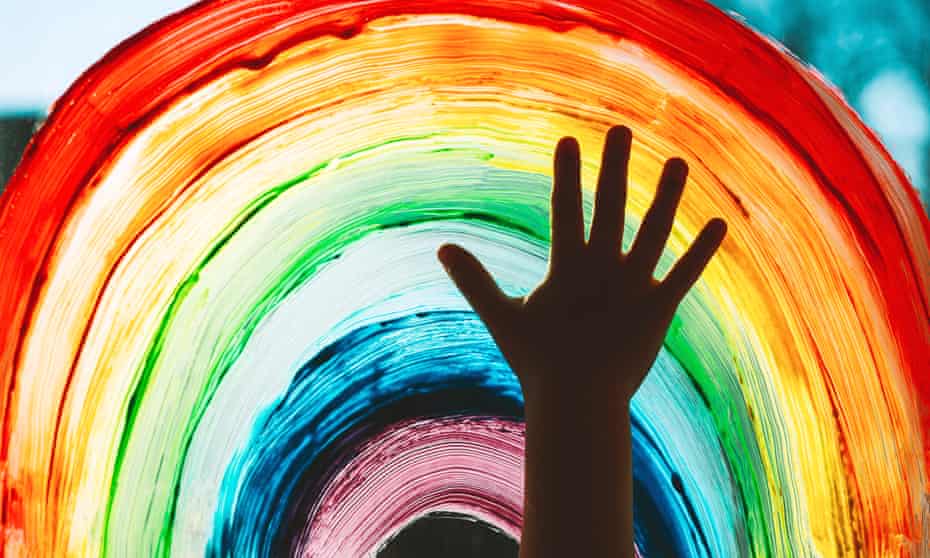 child's hand in front of painted rainbow