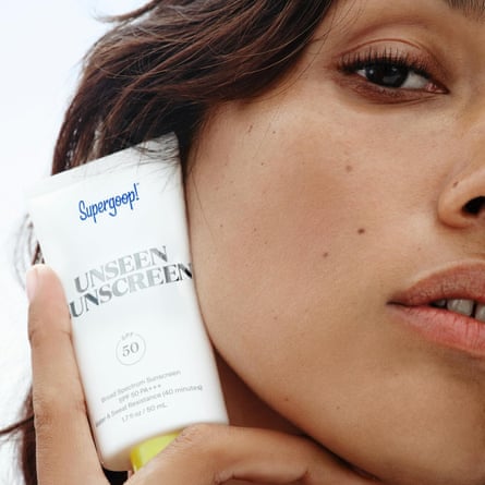 woman holds sunscreen close to face