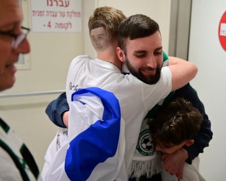 Matan Angrest is embraced by a man and a boy