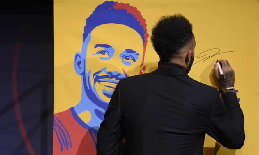 Pierre-Emerick Aubameyang signs a poster reading “welcome Aubameyang” at the Camp Nou.