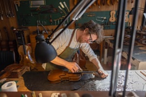man restoring a  violins in a workshop