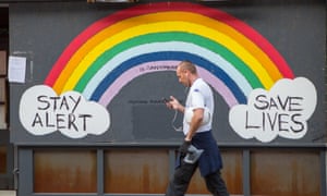 A man walks past a Stay Alert Save Lives rainbow sign in Soho, London, during the second lockdown.