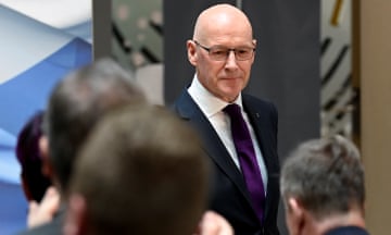 John Swinney pictured facing the camera with the backs of his audience's heads in the foreground