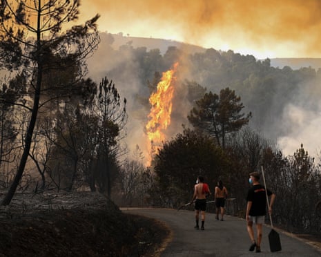 People walk by a burnt area during a wildfire near the village of Larouco, in the province of Ourense, in northwestern Spain.