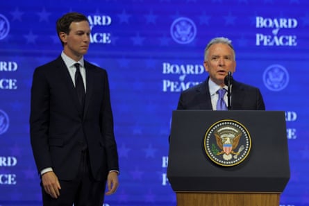 a man in a suit speaks into a microphone next to another man in a suit