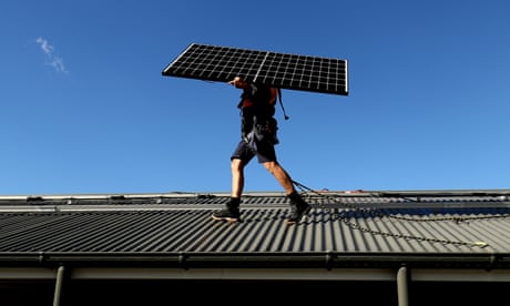 A worker installs solar panels on a roof