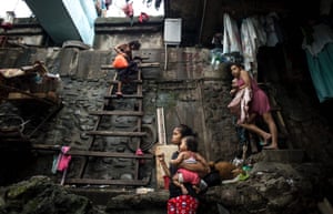 A woman climbs down a ladder where people live under a bridge after typhoon Sarika