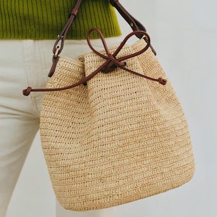 Sezane Farrow Bag made from natural Rraffia with a brown thread drawstring. The bag is shown in front of a models body.