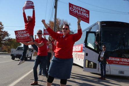 Susan Collins supporters cheer and raise campaign signs beside a bus