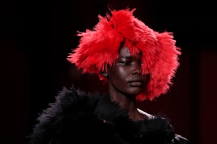A model wears a red-feather hat and a black dress with a feather trim