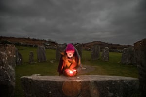 Amy Russell, uma xamã e curandeira, acendeu uma vela na pedra do altar enquanto esperava para observar o nascer do sol durante o círculo de pedras Drombeg fora de Glandore em Cork, Irlanda