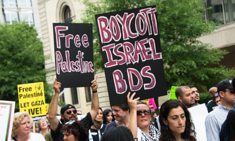 Protesters hold signs saying 'Free Palestine' and 'Boycott Israel BDS' during a protest