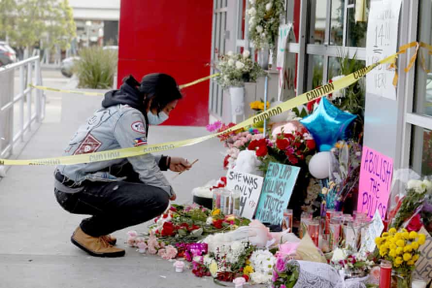 A man squats down to place sticks of incense at a memorial for Valentina Orellana-Peralta in front of Burlington Coat Factory's building.
