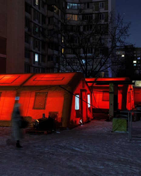 Red tents illuminated by light inside, next to high-rise blocks of flats.