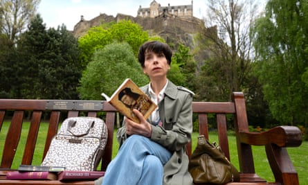 Sally Hawkins as Philippa Langley in The Lost King, sitting on a bench, with a book.