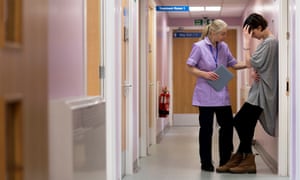 Nurse comforts young person in hospital corridor