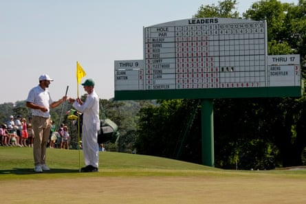 Scottie Scheffler gives his club to his caddie on the 18th hole after his third round at Augusta