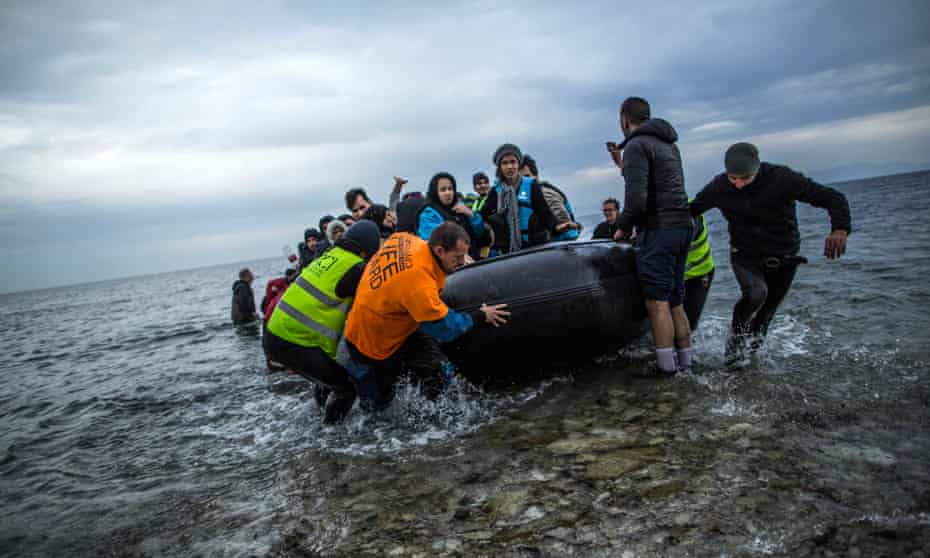 Refugees and migrants are helped by volunteers as they arrive in Lesbos in Greece