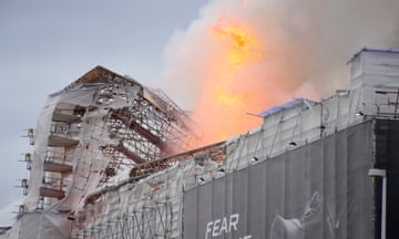 Flames and smoke rise from the building, which is covered in tarpaulin during renovation work