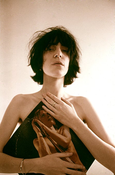 She holds a record sleeve against her apparently naked torso