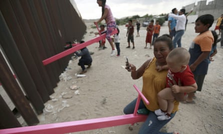 A mother and her baby play on a seesaw installed between the steel fence that divides Mexico from the United States in Ciudad de Juarez, Mexico in 2019.