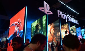 People wander in front of the Playstation posters at E3 in Los Angeles, California.
