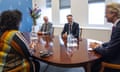 Three men and one woman sit around a wooden table. Wilders, with his trademark blond hair swept back from his face is side-on. Caroline van der Plas, the BBB leader, sits with her back to the camera. She has curly black hair. Opposite her are Schoof and another man, both wearing suits. All four are smiling and have their hands clasped and resting on the table.