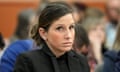 White woman with pulled-back brown hair and black blazer and shirt looking tense in what appears to be a courtroom.