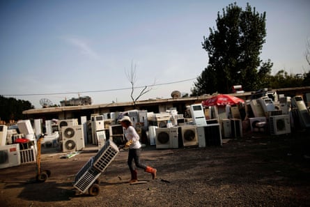 A recycling worker moves air-conditioning units in the yard of her tenement house at Dongxiaokou village in Beijing