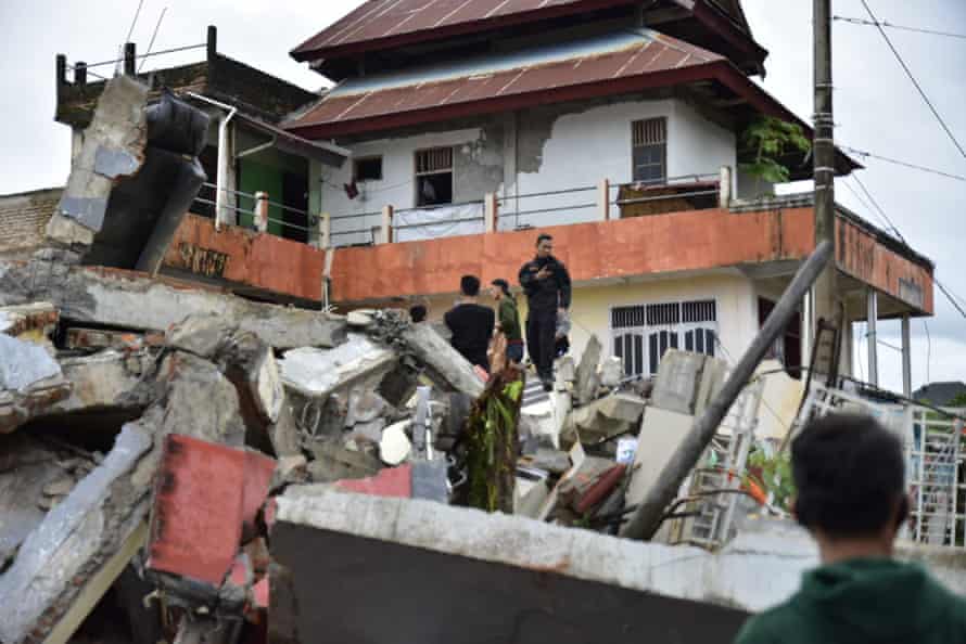 Rescuers search for survivors among the ruin of a building damaged by an earthquake in Mamuju