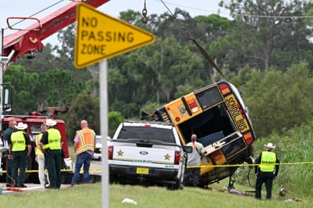 Crews work beside the road to flip an overturned school bus