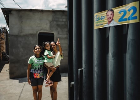 Rosimari Monteiro points at a campaign ad for Flávio Bolsonaro while standing with her daughters