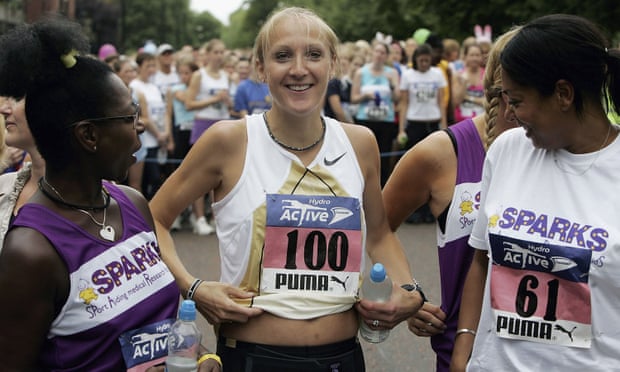 Paula Radcliffe running and smiling, holding up her T-shirt to show her belly at five months pregnant