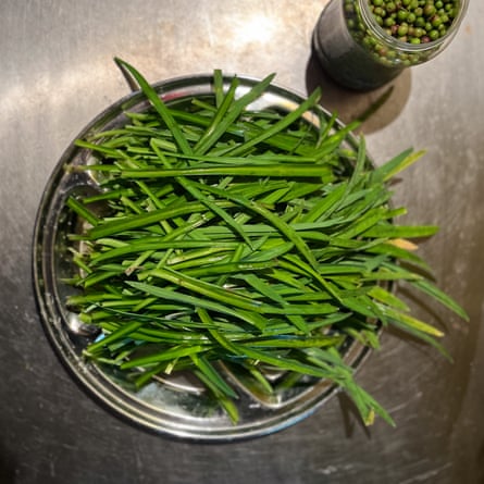 A metal bowl contains a green leafy vegetable. A jar next to it contains what looks like peas