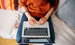 Overhead close up of a young woman working on laptop<br>Closeup overhead image of a young woman sitting on the sofa at her home, using her laptop. She could be casually browsing the web, reading, chatting with friends or doing some freelance job from home. Home relaxation or workspace concept in an modern living room space shot in vintage film emulation color grading.