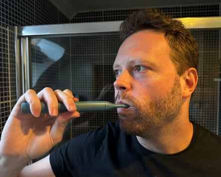The writer brushes his teeth with a Suri 2.0 toothbrush in his bathroom at home