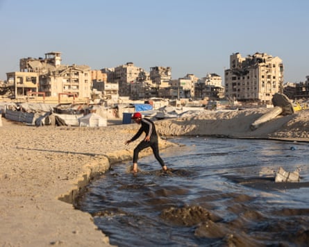 A man crosses effluent water that runs from the camps housing displaced families in Gaza City towards the Mediterranean.