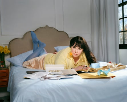 Lena Dunham lying on bed surrounded by papers and notepads