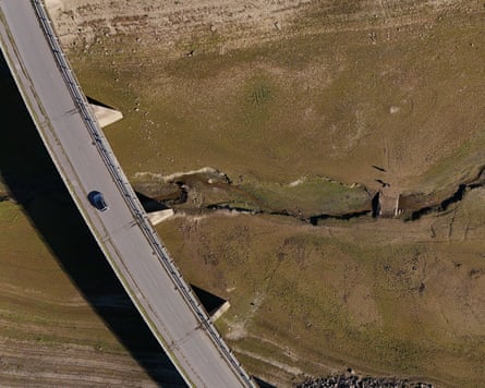 Aerial view of a car crossing a bridge above the re-emerged old stone Bessom Bridge, Wimbleball Lake