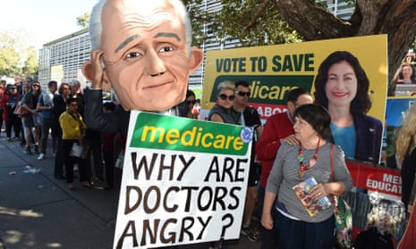 Protester wearing a giant puppet head of Malcolm Turnbull holds a sign criticising the government’s policy on Medicare