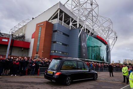 Fans applaud as the hearse carrying Sir Bobby Charlton passes Old Trafford.