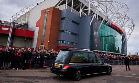 Fans applaud as a hearse carrying the coffin of Bobby Charlton is driven past Old Trafford before his funeral.