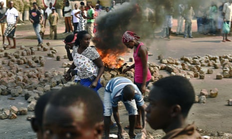 People walk past a barricade in Bujumbura, July 2015.