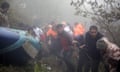 Rescuers link arms next to the wreckage in a misty forest