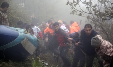 Rescuers link arms next to the wreckage in a misty forest