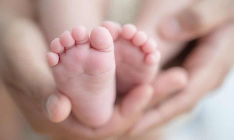 Feet of a newborn baby in the hands of parents