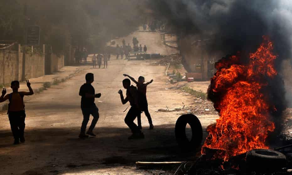 Palestinian children beside burning tyres after an Israeli military raid in Jenin on the West Bank