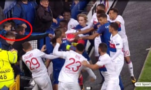An Everton fan holding a child gets involved as Everton and Lyon players clash.