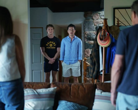 The lead characters from Heated Rivalry, Ilya and Shane, stand in a living room looking nervous and facing Shane’s parents.