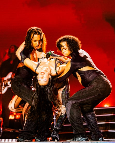 dua lipa leans back as dancers support her